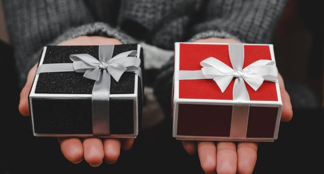 Gift boxes in female hands, close-up. Woman with red and black gift box